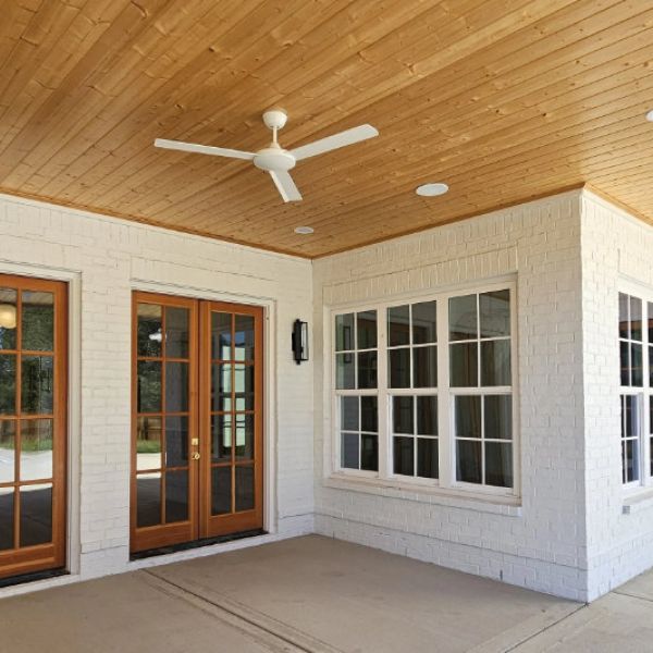 This covered porch features a wood panel ceiling and custom wood doors.