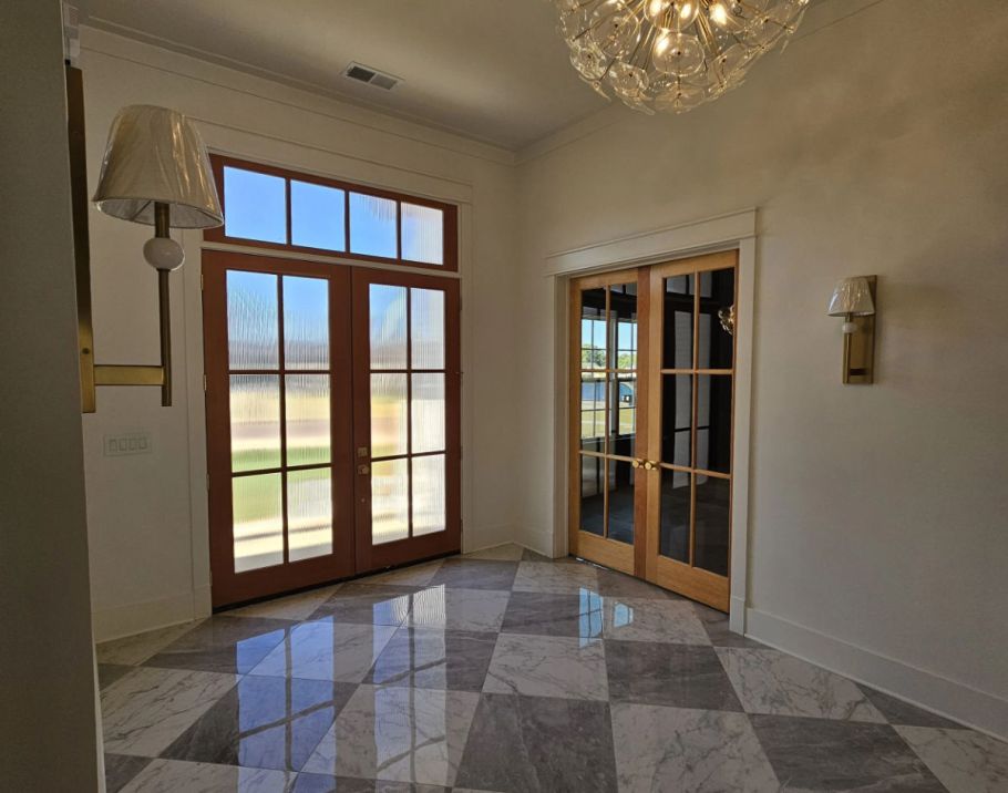 Custom home entry featuring marble floor and custom wood dorrs.